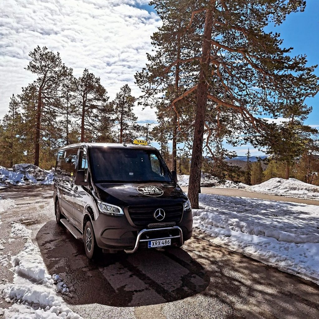 Ylläs Taxi Service van in a sunny winter forest, Lapland Finland